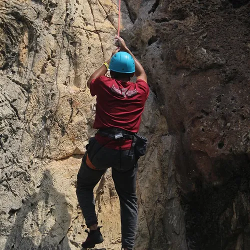 Amin Shennan rock climbing up a limestone wall on a rope